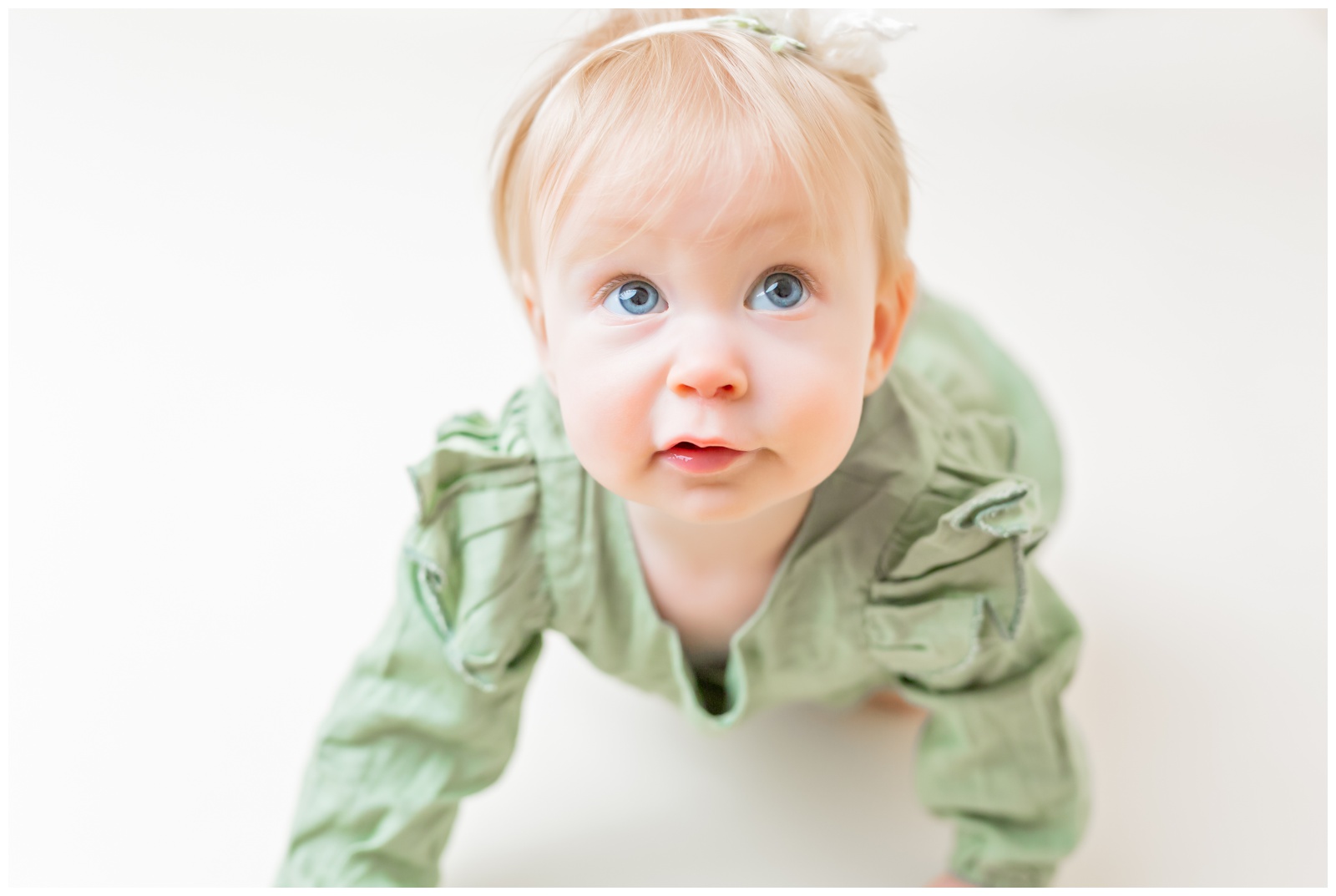 1 year old in green romper crawling, cake smash session