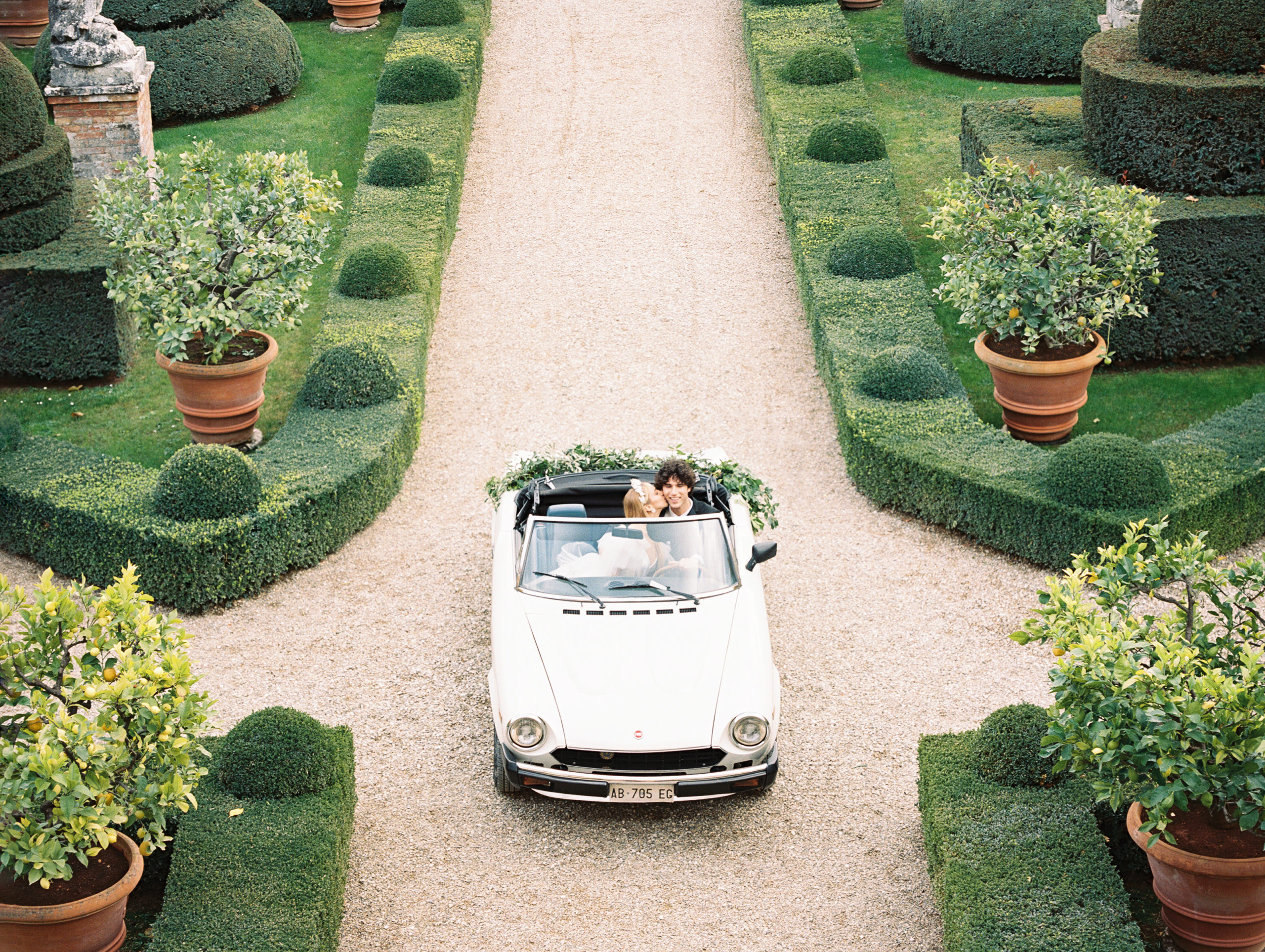 Bride kisses her groom in their convertible getaway car after their Tuscany, Italy wedding